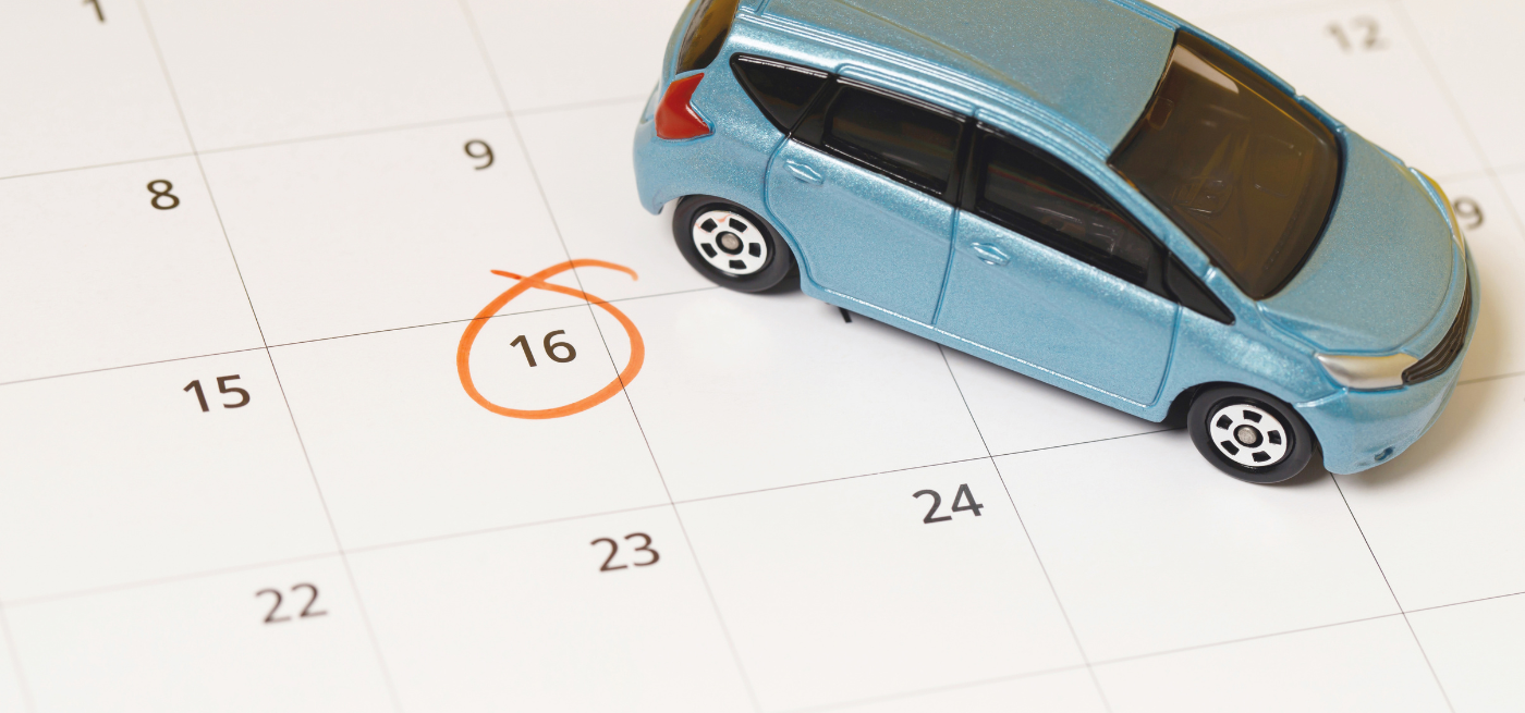 Carro em miniatura sobre um calendário com uma data assinalada a laranja