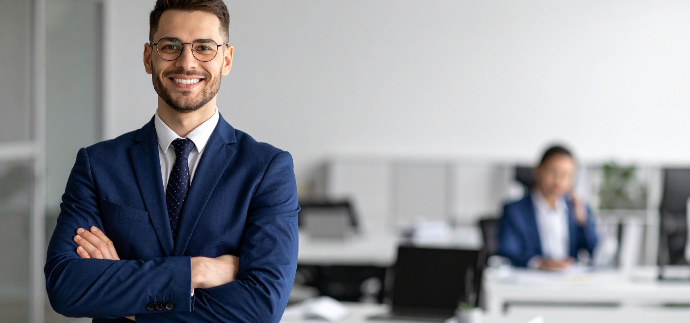 Homem de fato sorridente e braços cruzados num escritório, transmitindo confiança para empreender